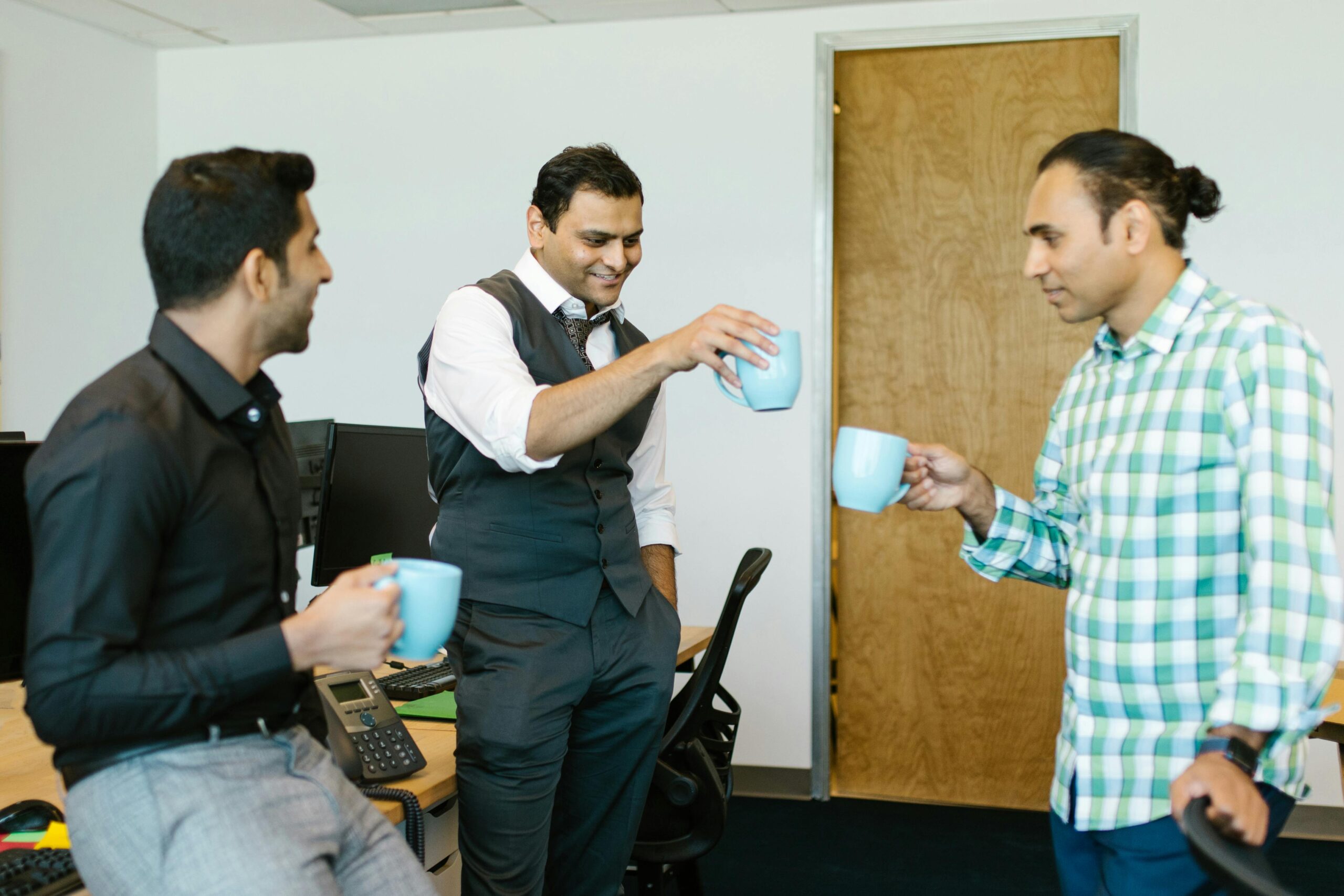 office workers chatting with mugs off coffee in hand