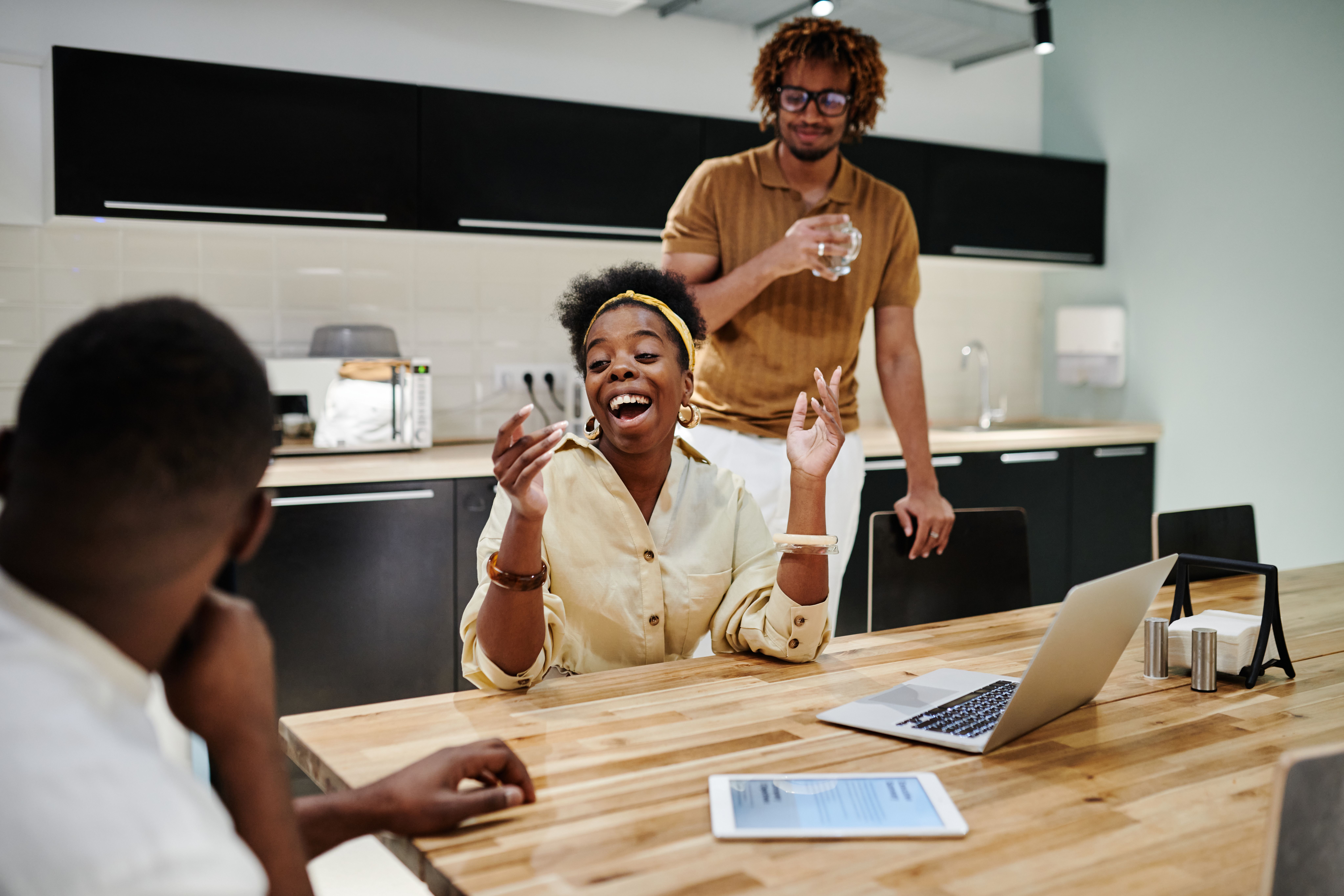 office employees in the breakroom laughing around the office water dispenser