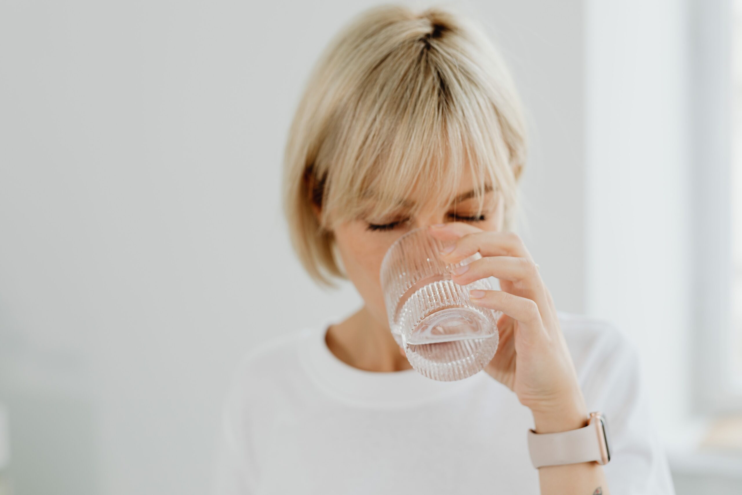 woman drinking water from a water dispenser in the office
