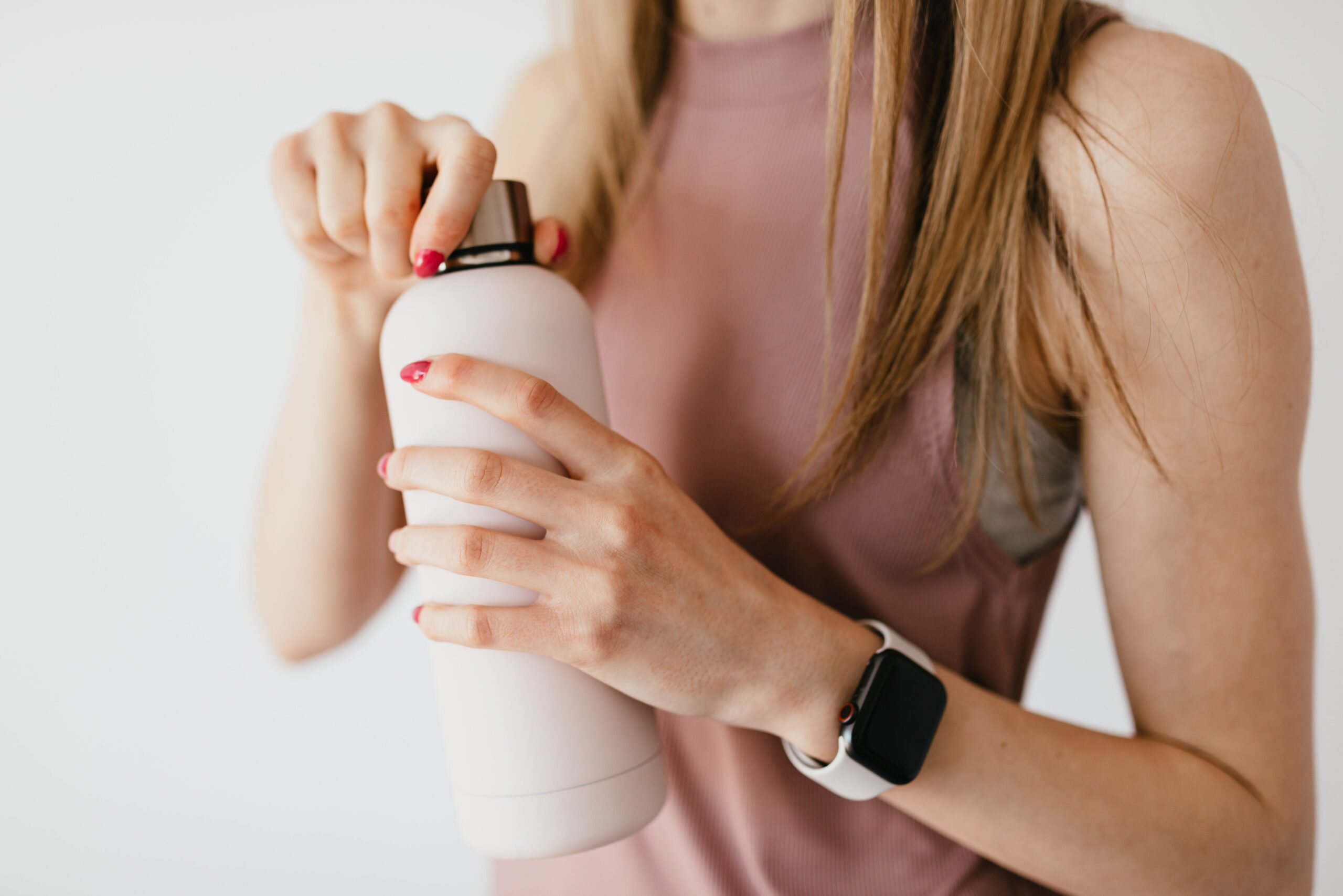woman opening her steel bottle of water during a gym workout